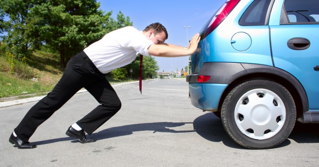 Man pushing car after breakdown