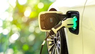EV Car or Electric car at charging station with the power cable supply plugged in on blurred nature with soft light background. Eco-friendly alternative energy concept